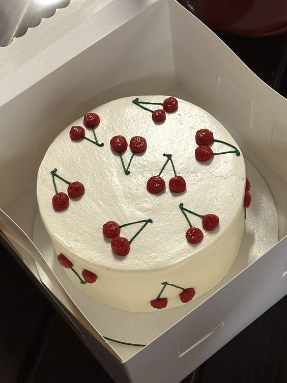 White frosted cake decorated with red cherries