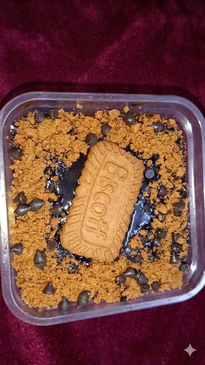 Dessert tub topped with biscuit crumbs, chocolate drizzle and a whole biscuit